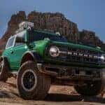 A green 2024 Ford Bronco Outer Banks driving down a hill.
