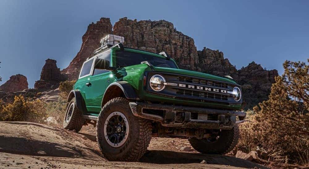 A green 2024 Ford Bronco Outer Banks driving down a hill.