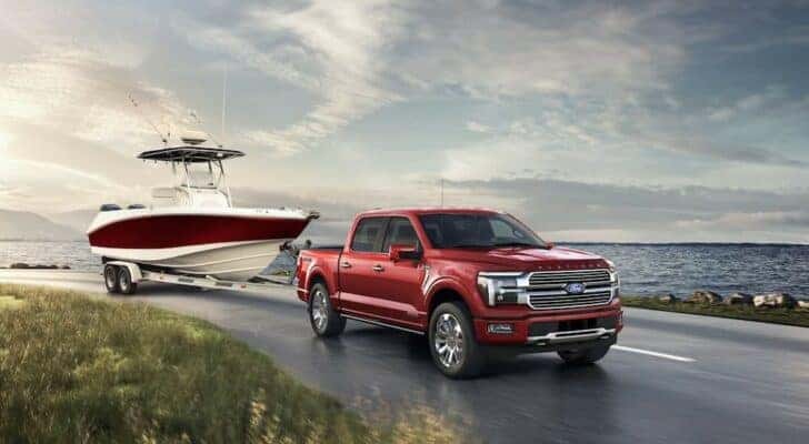 A red 2024 Ford F-150 Platinum is shown towing a boat.