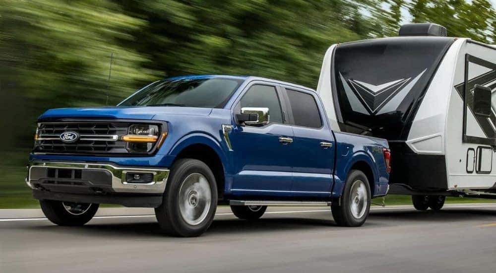 A blue 2024 Ford F-150 Tremor is shown towing a trailer.