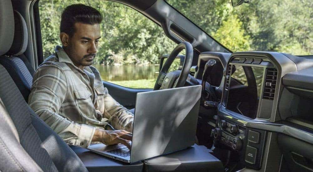 A person is shown using a laptop in a 2024 Ford F-150.