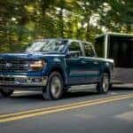 A blue 2024 Ford F-150 XLT towing a trailer.