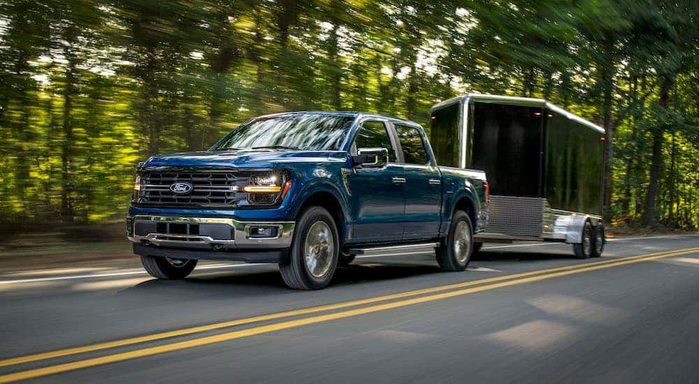 A blue 2024 Ford F-150 XLT towing a trailer.