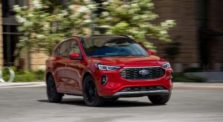 A red 2024 Ford Escape ST-Line is shown from the front at an angle after leaving a dealer that has a Ford Escape Plug-In Hybrid for sale.