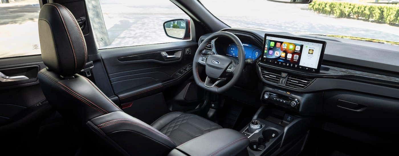 The black interior of a 2024 Ford Escape ST-Line is shown from the rear seat.