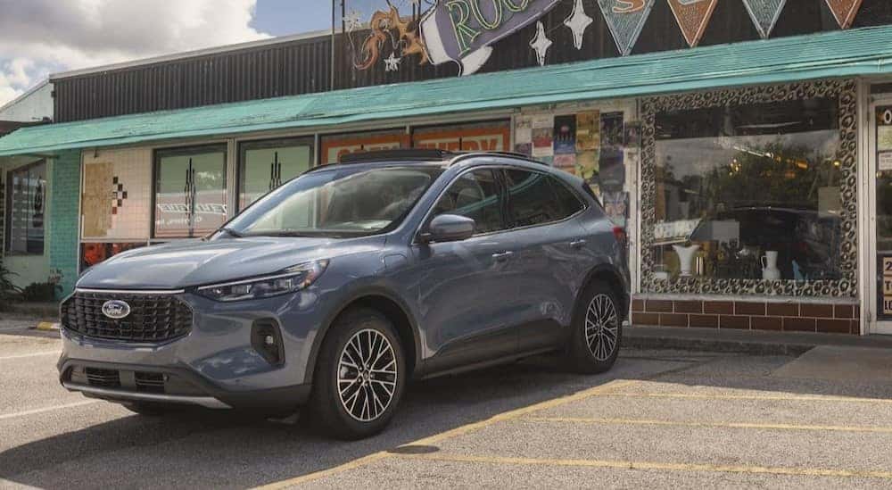 A gray 2024 Ford Escape Plug-in Hybrid for sale is shown parked near a store.