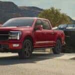 A red 2024 Ford F-150 is shown towing a boat.