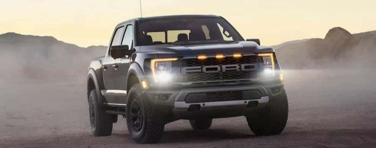 A gray 2024 Ford F-150 Raptor is shown parked off-road.