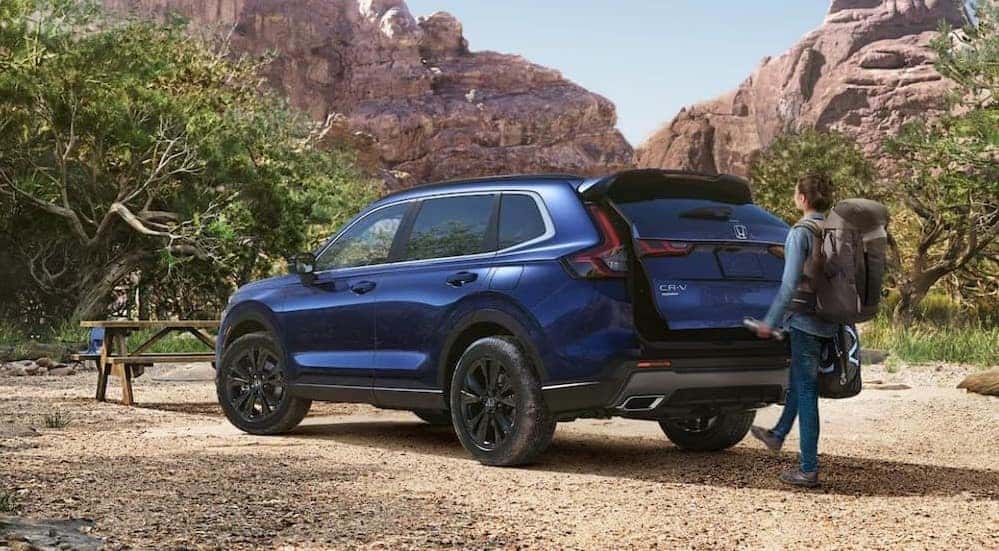 A blue 2025 Honda CR-V Sport Touring Hybrid is shown parked off-road.