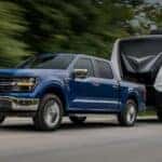 A blue 2025 Ford F-150 towing a trailer.