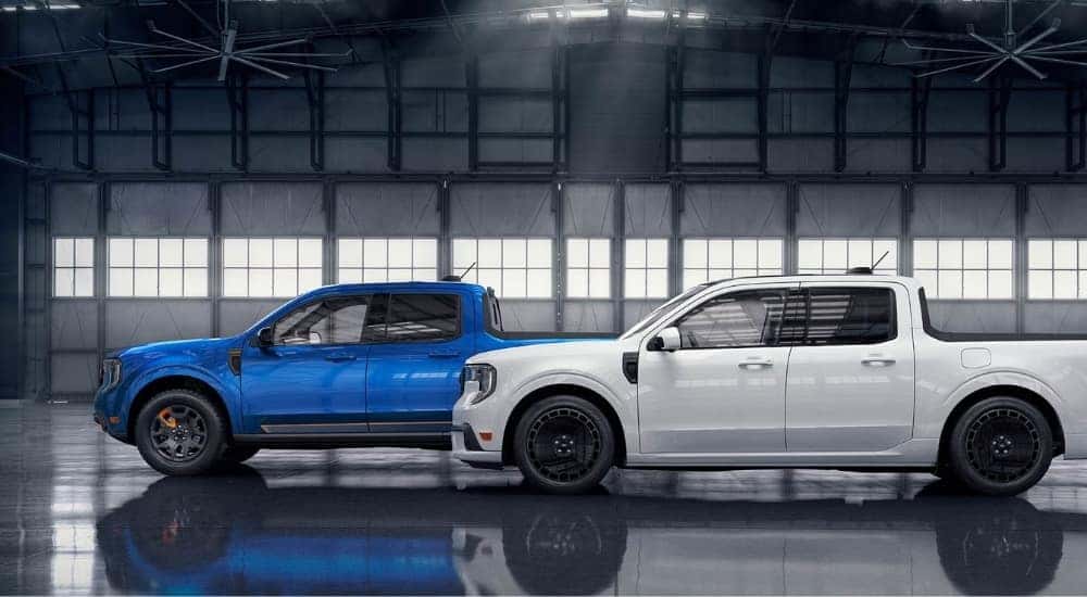 A blue 2025 Ford Maverick Tremor and white Maverick Lobo are shown in a warehouse.