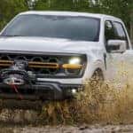 A white 2025 Ford F-150 Tremor is shown kicking up mud after leaving a Ford dealer near West Chester.