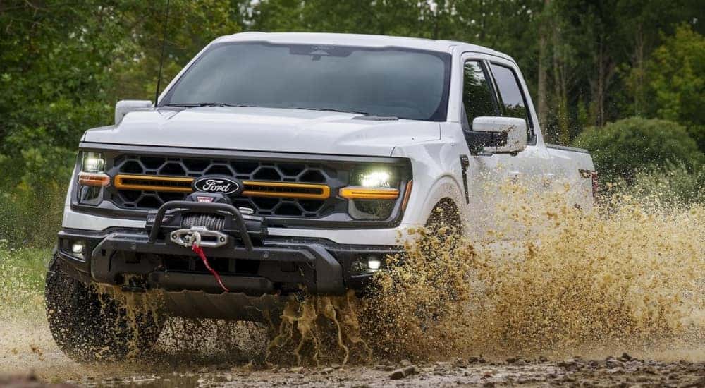 A white 2025 Ford F-150 Tremor is shown kicking up mud after leaving a Ford dealer near West Chester.
