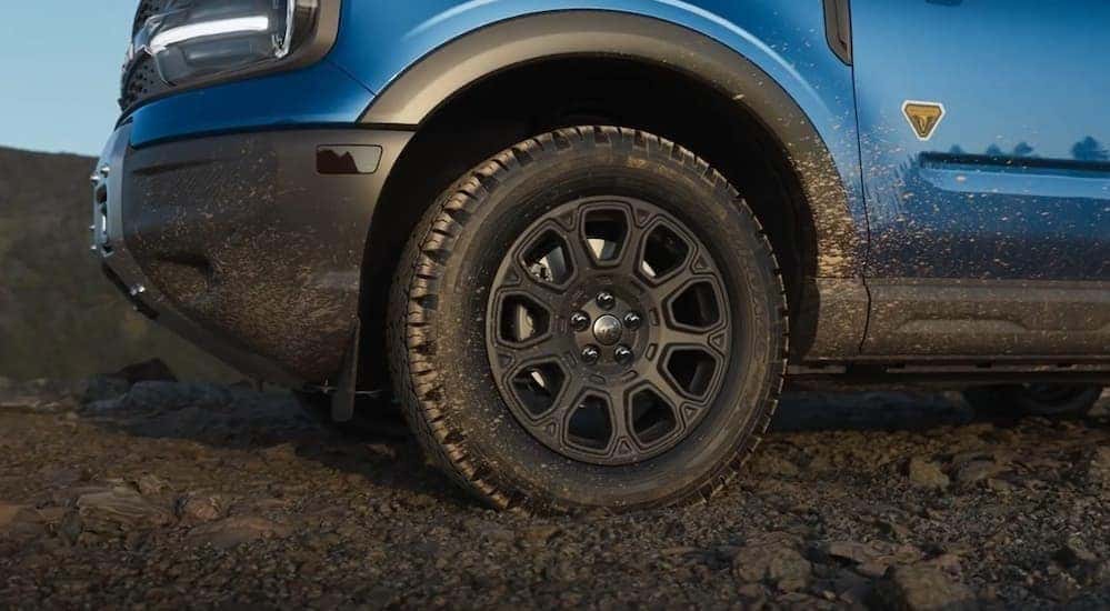A close-up of the wheel on a blue 2025 Ford Bronco Sport Badlands is shown.