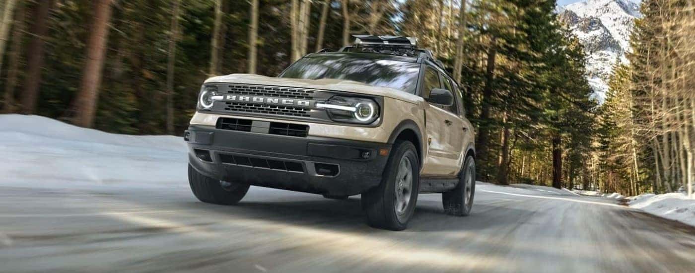 A tan 2024 Ford Bronco Sport Badlands driving through a forest.