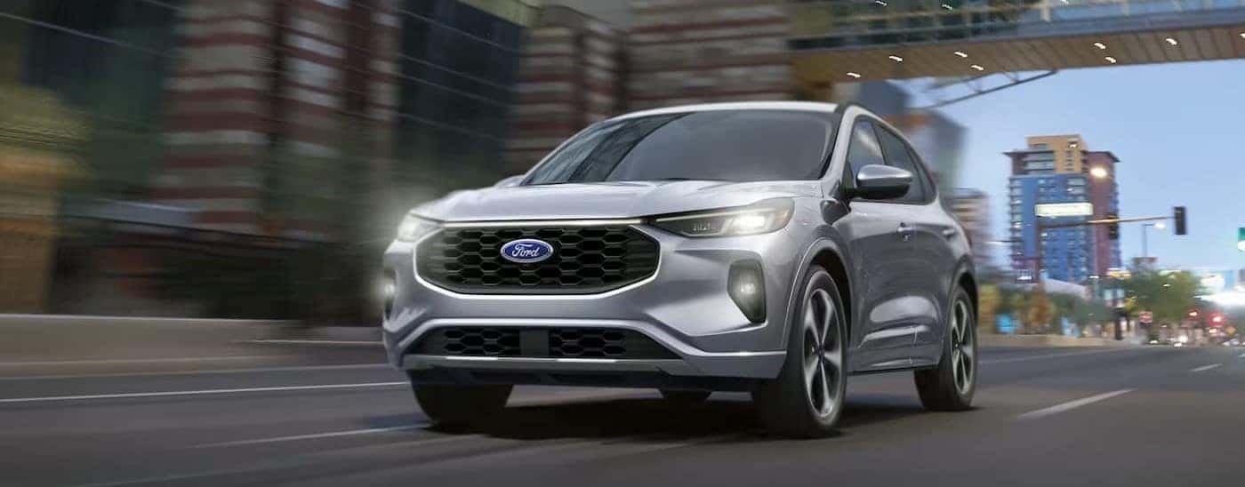 A silver 2024 Ford Escape is shown driving on a city street.