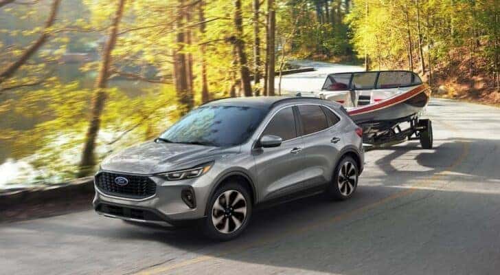 A silver 2024 Ford Escape for sale in Cincinnati is shown towing a boat.