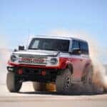 A white and orange 2025 Ford Bronco Stroppe Edition driving off-road.