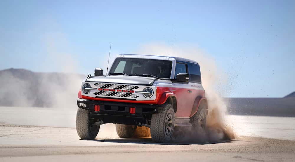 A white and orange 2025 Ford Bronco Stroppe Edition driving off-road.