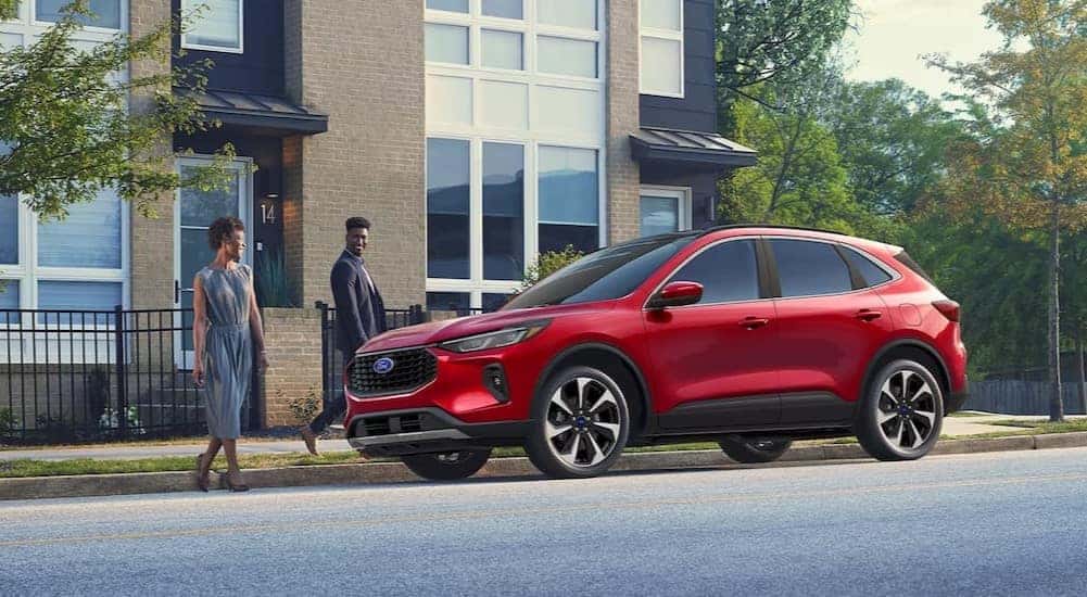 Two people are shown walking towards a red 2025 Ford Escape Platinum.