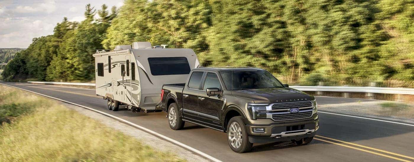 A brown 2025 Ford F-150 Platinum towing a silver camper.