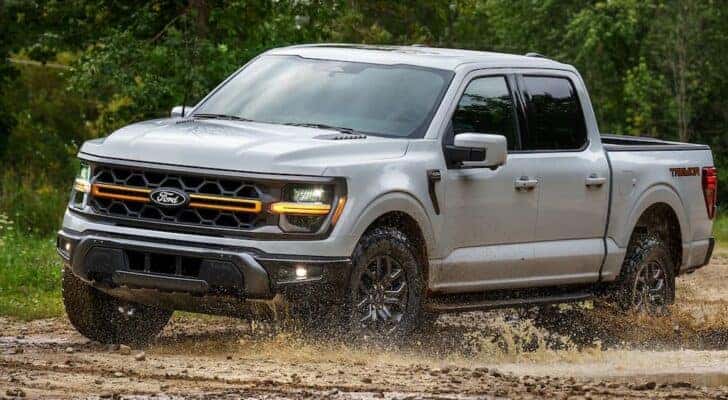 A grey 2025 Ford F-150 Tremor off-roading in mud.