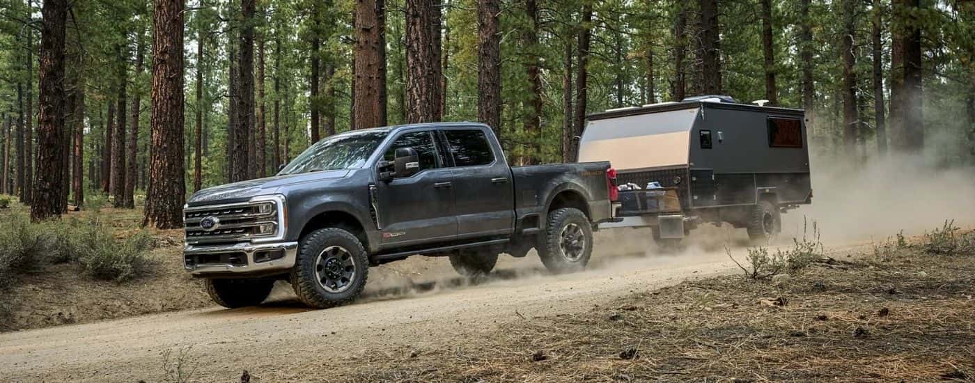 A grey 2025 Ford F-250 Lariat Tremor is towing a trailer on a dusty trail.