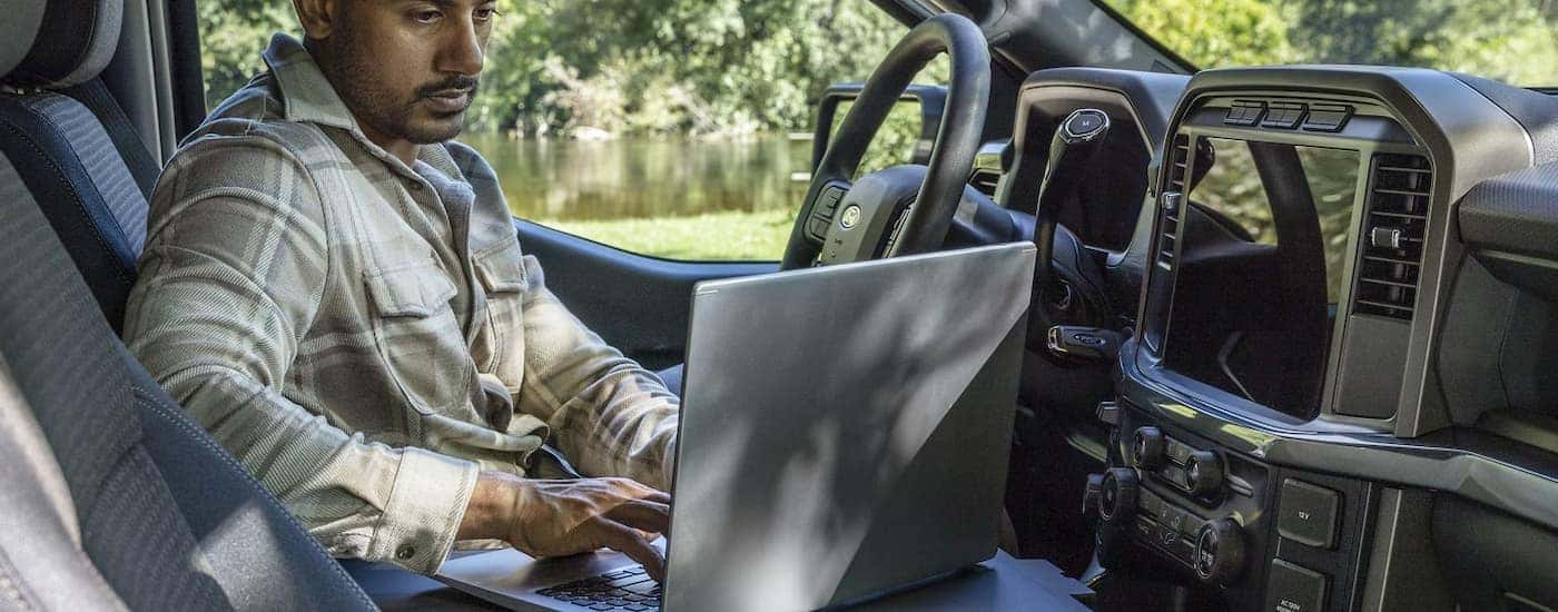 Man working on a laptop in a 2025 Ford F-150 at a Ford dealer near Fairfield.