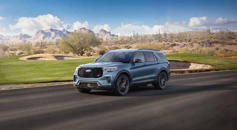 A blue 2025 Ford Explorer ST driving near a golf course.