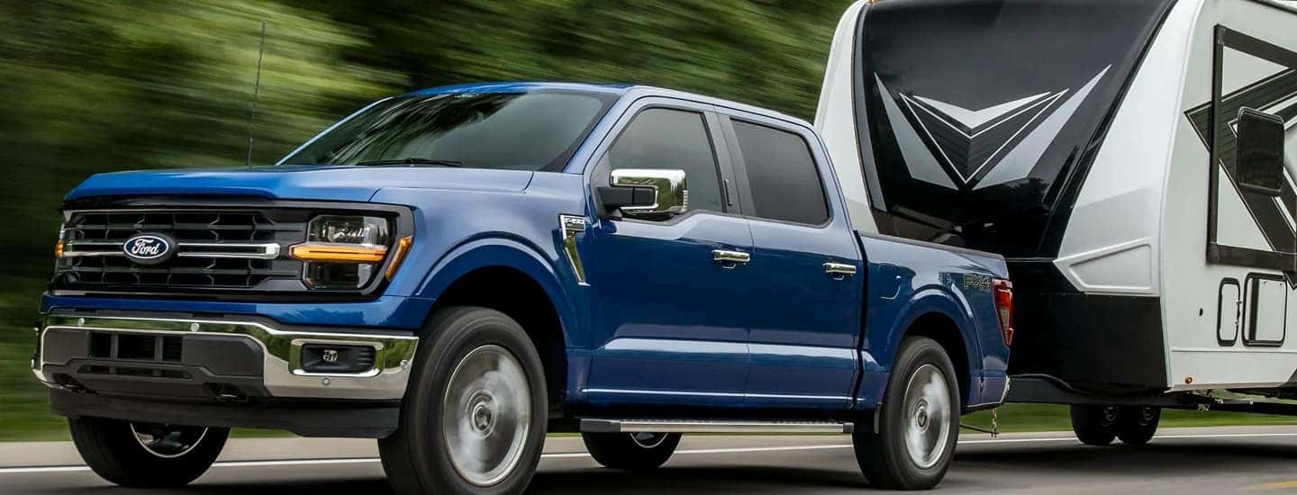 A blue 2025 Ford F-150 towing a camper behind it