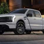 A gray 2025 Ford F-150 Lightning charging in a driveway