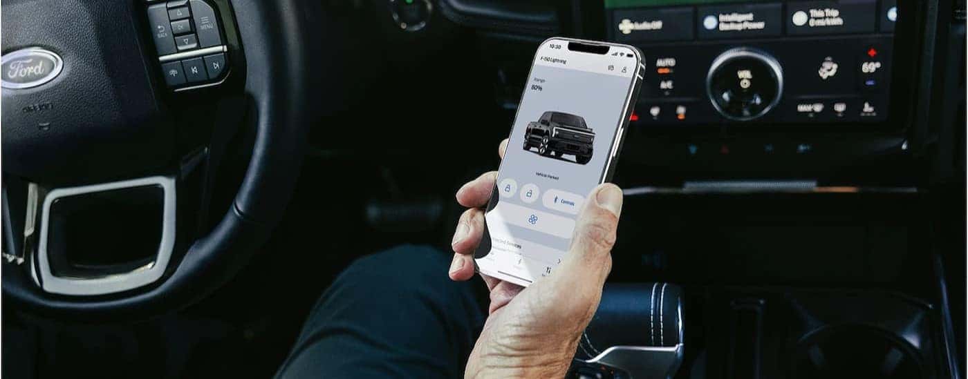 A person using a cell phone in a 2025 Ford F-150 Lightning.