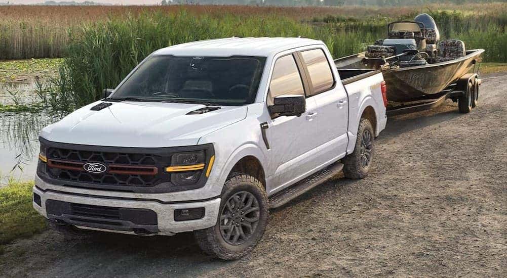 A white 2025 Ford F-150 STX towing a boat.