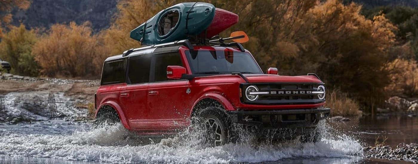 Red 2025 Ford Bronco Outer Banks driving over a shallow pond.