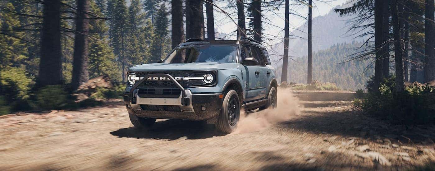 A blue 2025 Ford Bronco Sport off-roading on a dirt trail