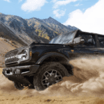 Black 2025 Ford Bronco driving off-road from the side at an angle.