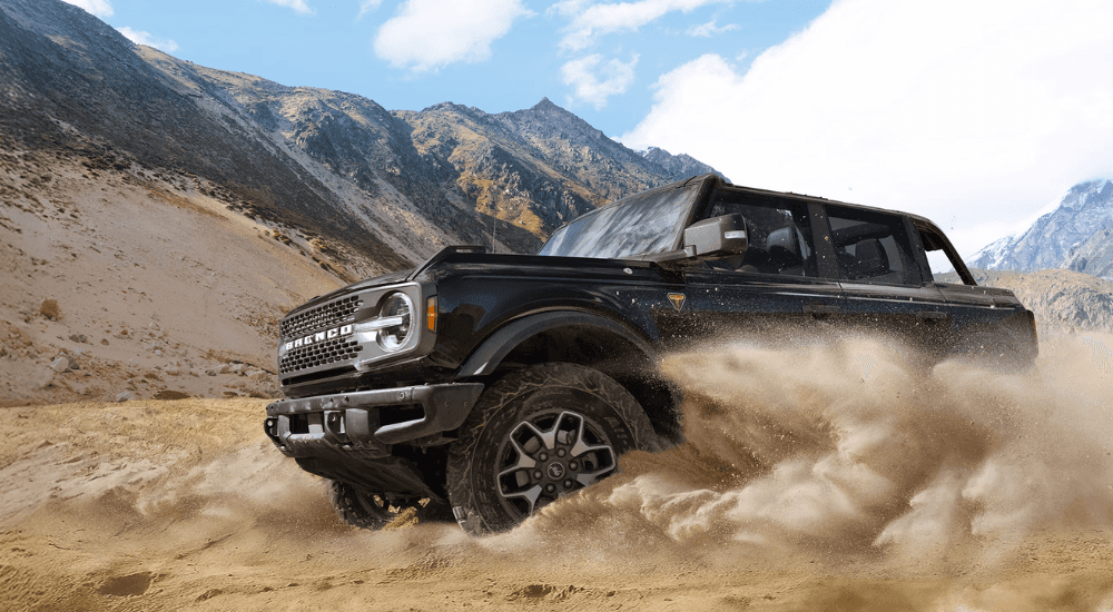 Black 2025 Ford Bronco driving off-road from the side at an angle.