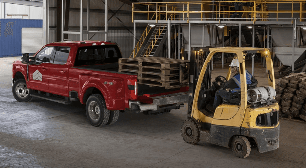 Red 2026 Ford F-350 with DRW having a forklift load the bed