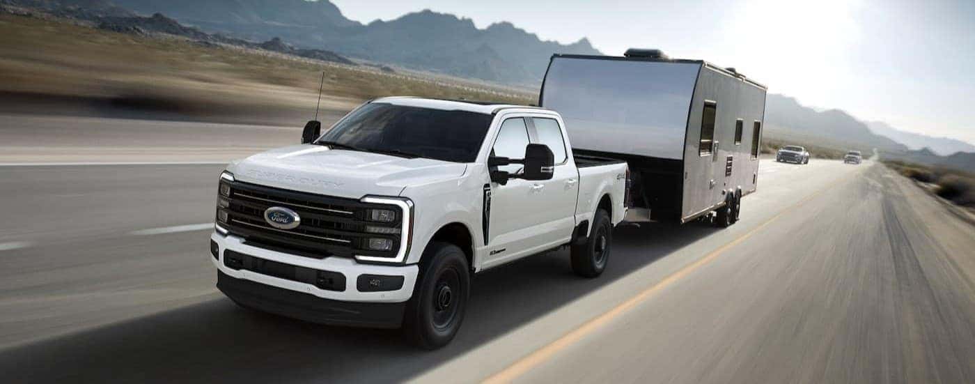 A white 2025 Ford F-350 towing a trailer.