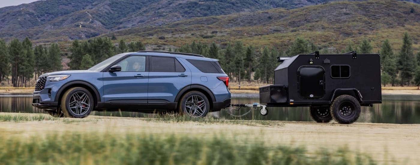 Blue 2025 Ford Explorer ST towing a camper off-road