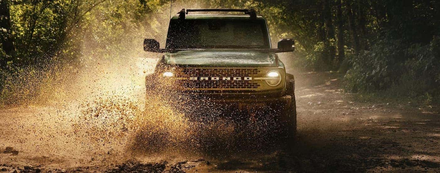 A green 2025 Ford Bronco driving through water.