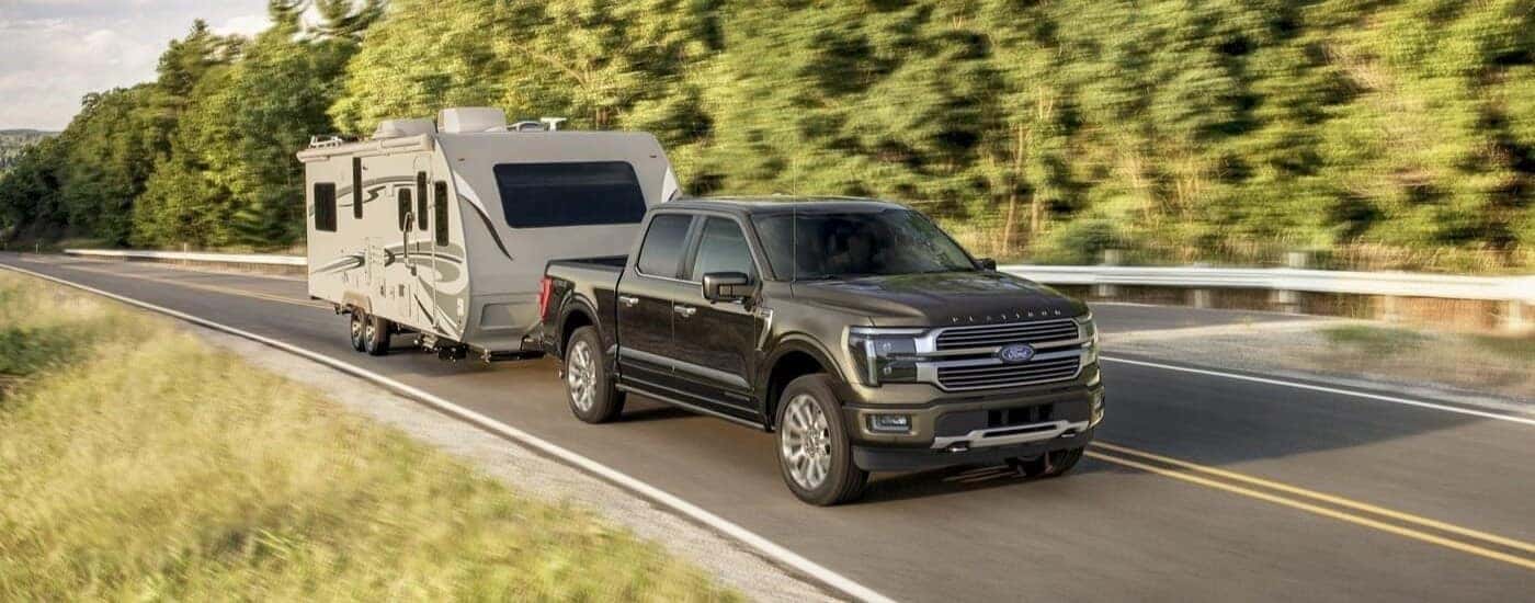 Black 2024 Ford F-150 Platinum Plus towing a van.