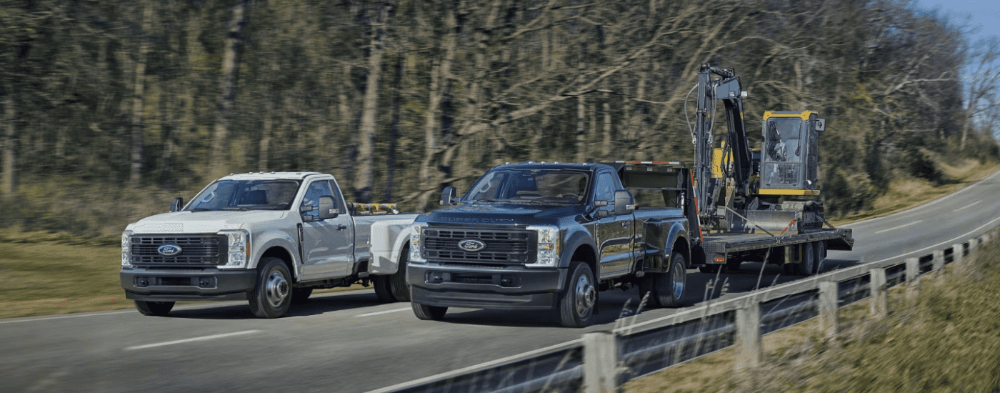 White Ford F-350 and black Ford F-450 both towing heavy machinery