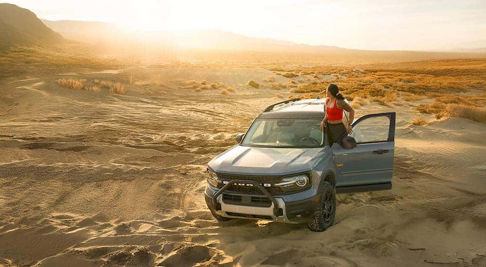 Person standing near a blue 2026 Ford Bronco Sport parked off-road.