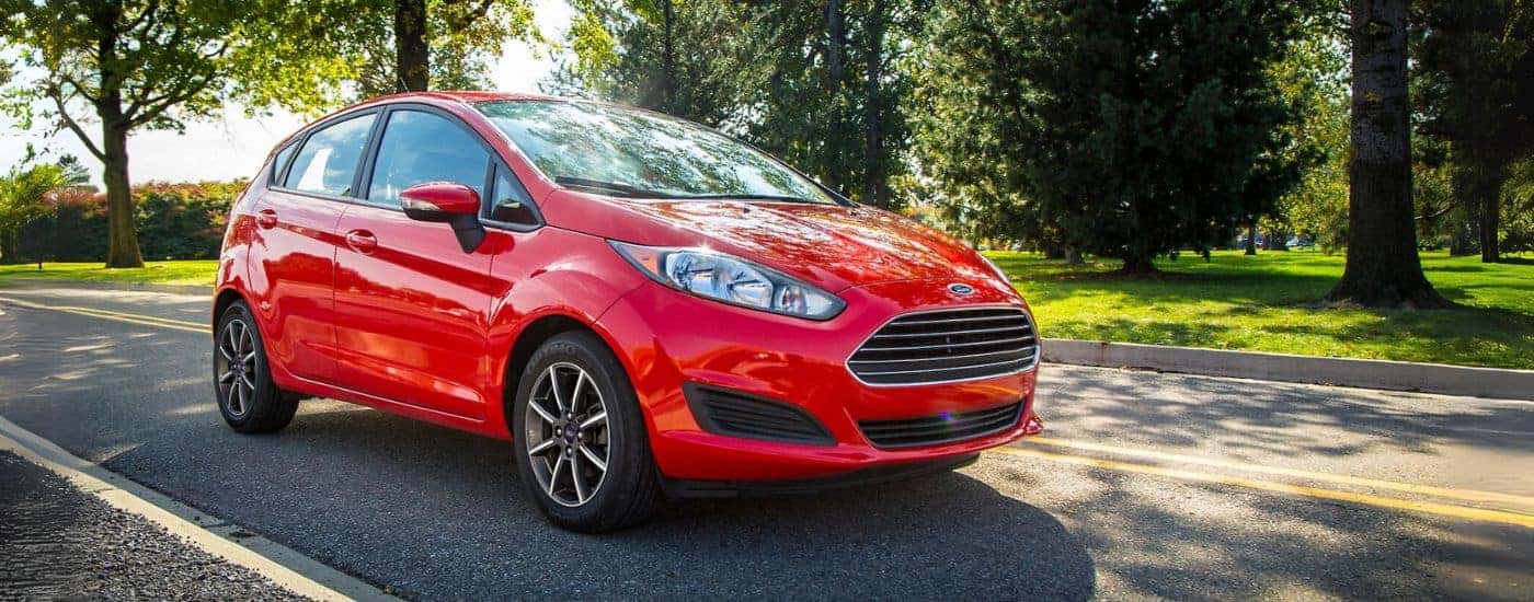 A red 2015 Ford Fiesta shown driving by trees.