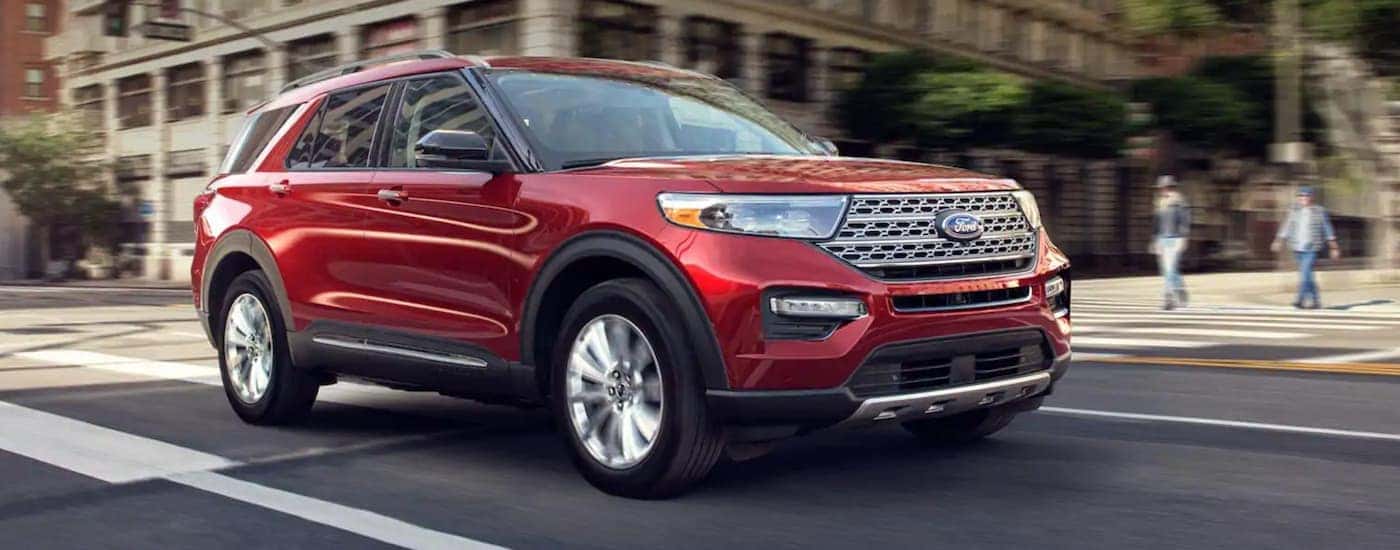A red 2020 Ford Explorer is shown driving a city street.