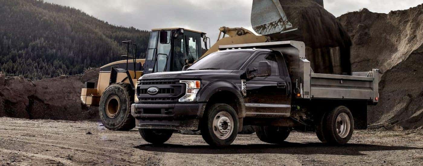 Grey 2020 Ford F-600 being loaded on a construction site.