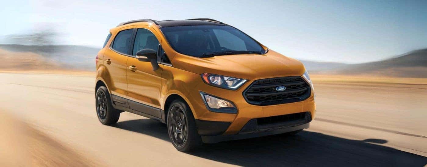 An orange 2021 Ford EcoSport is shown driving on a sandy road.