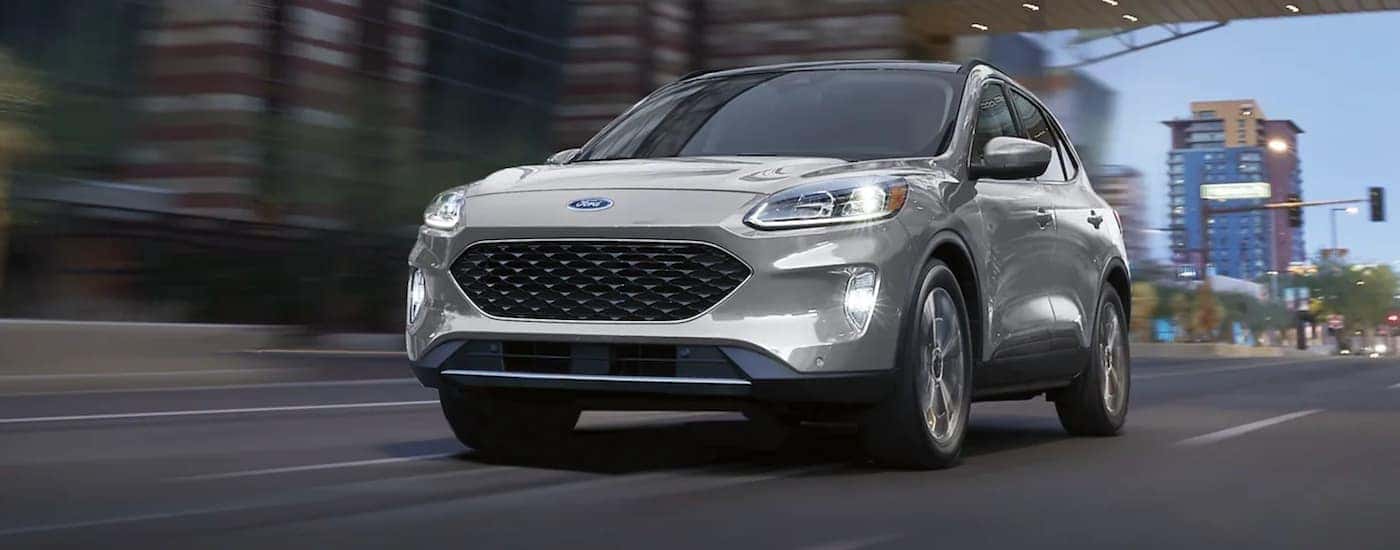 A silver 2021 Ford Escape Titanium is shown driving on a city street.