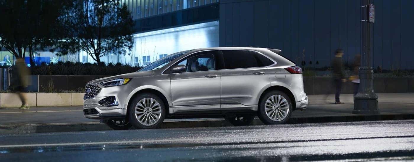 A silver 2024 Ford Edge for sale is shown parked near a building.